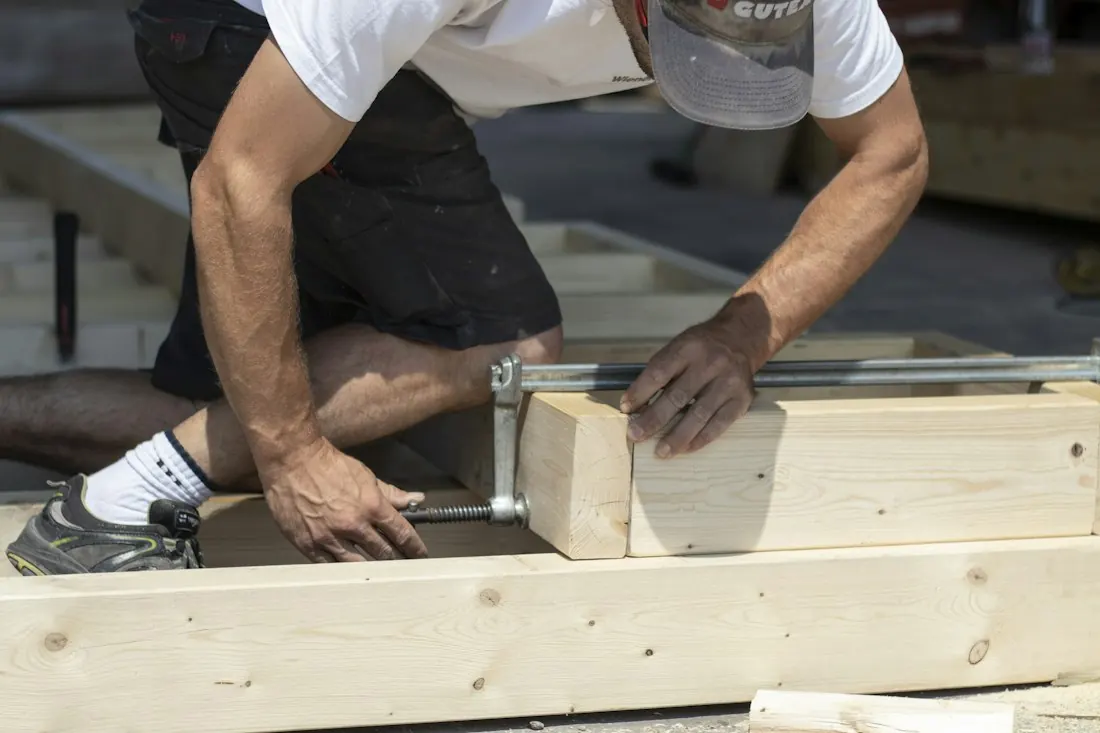 Handwerker misst ein Kantholz mit dem Maßband